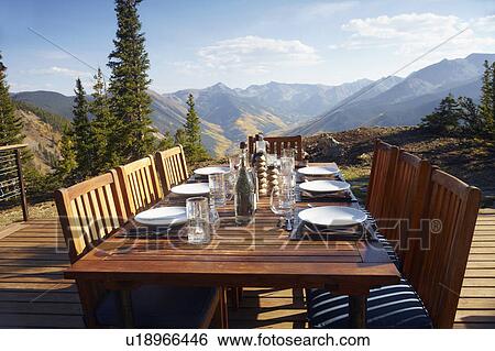 Stock Photograph - Outdoor table and chairs on wooden terrace. Fotosearch