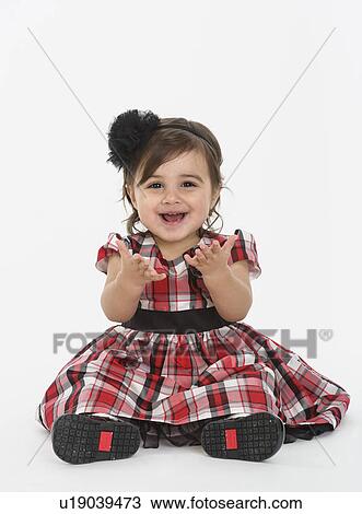 Stock Image - Portrait of Baby girl ( 6-11 months) wearing plaid dress. Fotosearch
