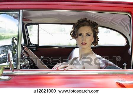 Stock Image - Portrait of elegant woman in vintage car. Fotosearch