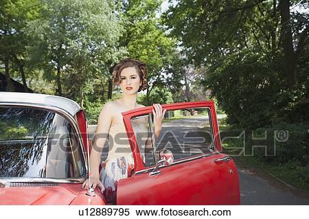 Stock Photography - Portrait of elegant woman next to vintage car. Fotosearch