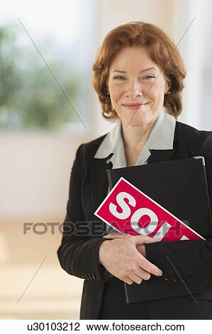 Portrait of female real estate agent holding sold sign View Large Photo Image Stock Image - Portrait of female real estate agent holding sold sign. Fotosearch