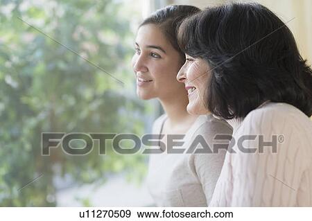 Portrait of grandmother and granddaughter (16-17) looking through window View Large Photo Image Stock Photo - Portrait of grandmother and granddaughter (16-17) looking through window. Fotosearch