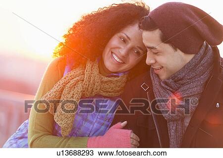 Stock Image - Portrait of happy couple embracing at sunset. Fotosearch