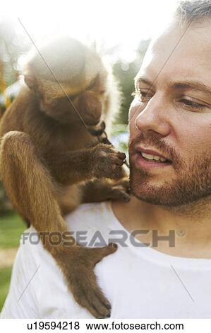 Stock Photo - Portrait of man holding monkey. Fotosearch