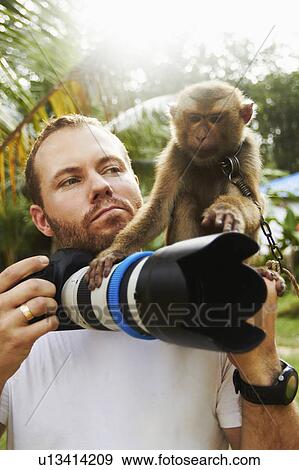 Stock Photo - Portrait of man with camera and macaque monkey. Fotosearch