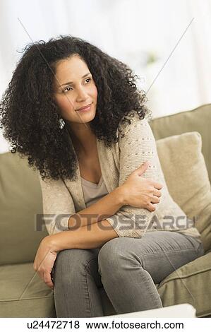 Stock Photo - Portrait of mid adult woman sitting on sofa. Fotosearch