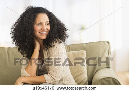 Portrait of mid adult woman sitting on sofa View Large Photo Image Stock Photograph - Portrait of mid adult woman sitting on sofa. Fotosearch