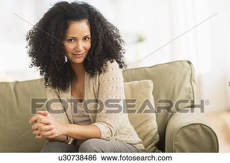 Portrait of mid adult woman sitting on sofa View Large Photo Image Stock Photograph - Portrait of mid adult woman sitting on sofa. Fotosearch