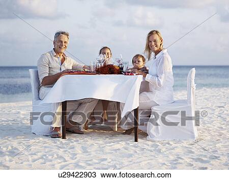 Portrait of parents with daughters (8-9), (4-5) sitting at table on beach View Large Photo Image Stock Image - Portrait of parents with daughters (8-9), (4-5) sitting at table on beach. Fotosearch
