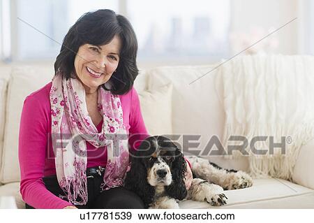 Stock Photo - Portrait of senior woman sitting on sofa with her dog. Fotosearch