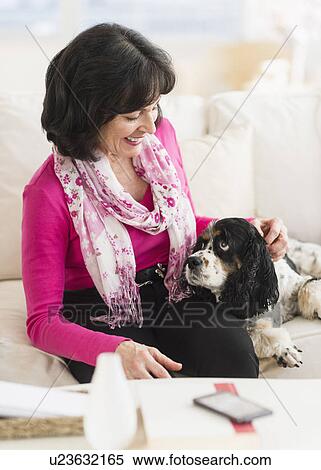 Stock Photography - Portrait of senior woman sitting on sofa with her dog. Fotosearch