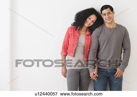 Portrait of smiling couple standing against white wall View Large Photo Image Stock Photo - Portrait of smiling couple standing against white wall. Fotosearch
