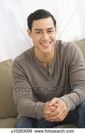 Portrait of smiling man sitting on sofa View Large Photo Image Stock Photo - Portrait of smiling man sitting on sofa. Fotosearch