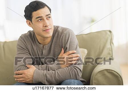 Stock Photo - Portrait of smiling man sitting on sofa. Fotosearch