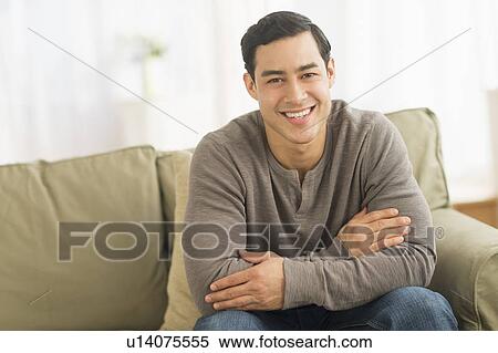 Portrait of smiling man sitting on sofa View Large Photo Image Stock Photography - Portrait of smiling man sitting on sofa. Fotosearch