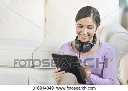 Stock Photo - Portrait of teenage girl (16-17) with digital tablet and headphones. Fotosearch