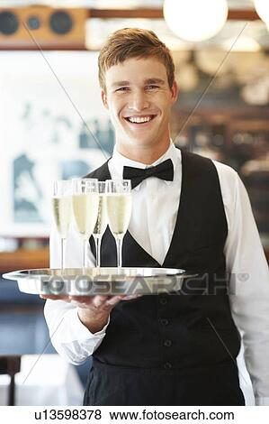 Stock Photo - Portrait of waiter holding champagne flutes on tray. Fotosearch