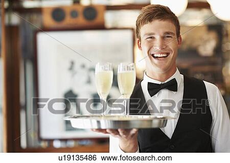 Portrait of waiter holding champagne flutes on tray View Large Photo Image Stock Photograph - Portrait of waiter holding champagne flutes on tray. Fotosearch