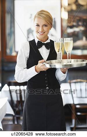 Portrait of waitress holding champagne flutes on tray View Large Photo Image Stock Photo - Portrait of waitress holding champagne flutes on tray. Fotosearch