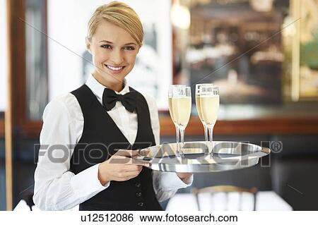 Stock Photograph - Portrait of waitress holding champagne flutes on tray. Fotosearch