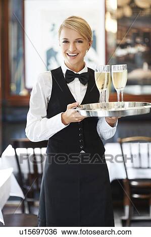 Stock Photograph - Portrait of waitress holding champagne flutes on tray. Fotosearch