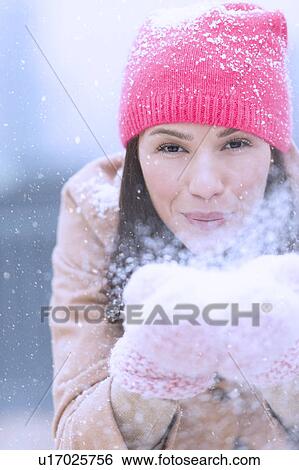 Stock Photograph - Portrait of woman blowing snow from hands. Fotosearch