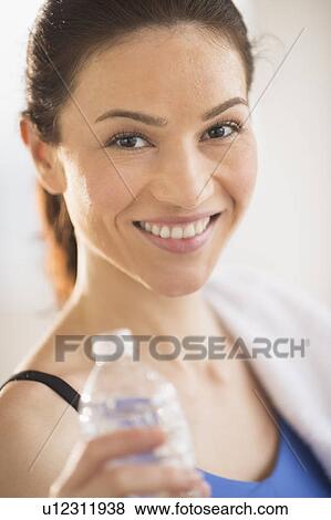 Portrait of woman drinking water in gym View Large Photo Image Stock Photo - Portrait of woman drinking water in gym. Fotosearch