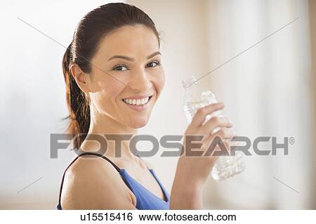 Stock Photograph - Portrait of woman drinking water in gym. Fotosearch