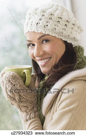 Stock Image - Portrait of woman in warm clothes holding mug. Fotosearch