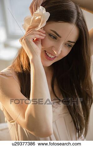 Stock Photograph - Portrait of young attractive woman with flower in hair. Fotosearch