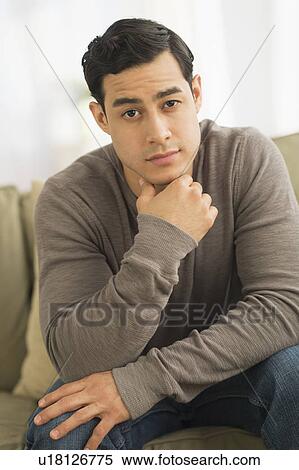 Stock Photography - Portrait of young man sitting on sofa. Fotosearch