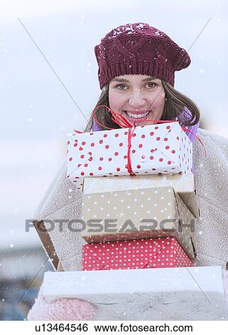 Portrait of young woman carrying stack of Christmas presents View Large Photo Image Stock Photograph - Portrait of young woman carrying stack of Christmas presents. Fotosearch