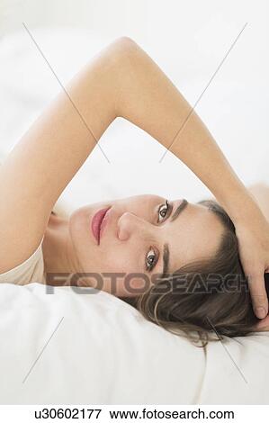 Stock Photo - Portrait of young woman lying in bed. Fotosearch