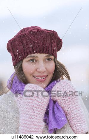 Stock Image - Portrait of young woman wearing knit hat, gloves and scarf. Fotosearch