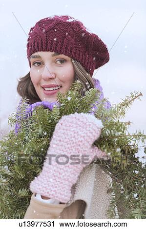 Portrait of young woman wearing knit hat, gloves and scarf an carrying fir wreath View Large Photo Image Stock Image - Portrait of young woman wearing knit hat, gloves and scarf an carrying fir wreath. Fotosearch