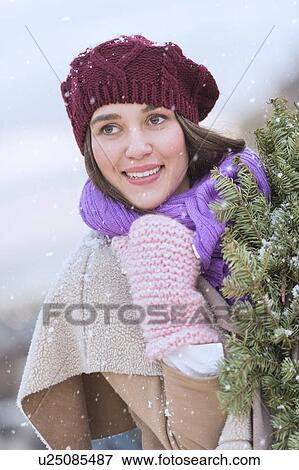 Portrait of young woman wearing knit hat, gloves and scarf an carrying fir wreath View Large Photo Image Stock Photo - Portrait of young woman wearing knit hat, gloves and scarf an carrying fir wreath. Fotosearch