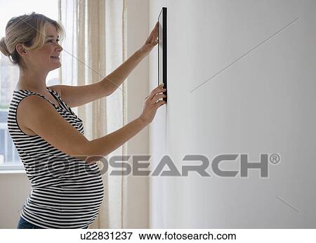 Pregnant woman decorating room View Large Photo Image Stock Photo - Pregnant woman decorating room. Fotosearch