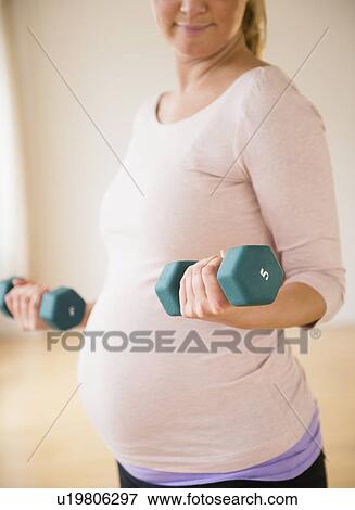 Stock Photo - Pregnant woman exercising with dumbbell. Fotosearch