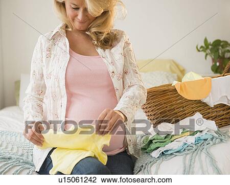 Pregnant woman folding baby clothes View Large Photo Image Stock Image - Pregnant woman folding baby clothes. Fotosearch