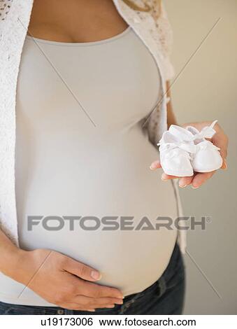 Pregnant woman holding baby shoes View Large Photo Image Stock Photograph - Pregnant woman holding baby shoes. Fotosearch