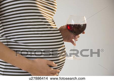 Pregnant woman holding glass of red wine View Large Photo Image Picture - Pregnant woman holding glass of red wine. Fotosearch