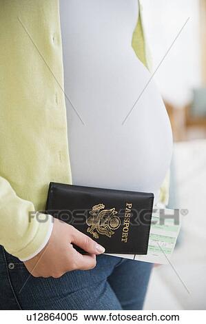 Stock Photography - Pregnant woman holding passport and flight tickets. Fotosearch
