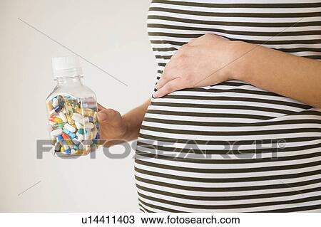 Pregnant woman holding vial with pills View Large Photo Image Stock Image - Pregnant woman holding vial with pills. Fotosearch
