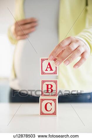Stock Image - Pregnant woman playing with bricks. Fotosearch