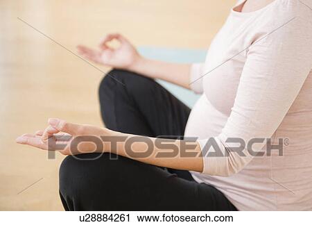 Stock Image - Pregnant woman practicing yoga. Fotosearch