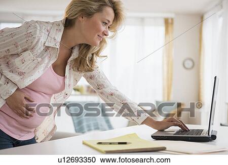 Stock Image - Pregnant woman using laptop. Fotosearch