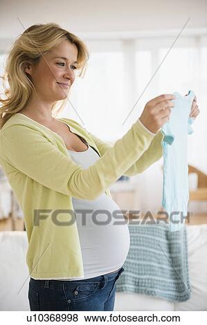 Pregnant woman with baby clothes View Large Photo Image Stock Photo - Pregnant woman with baby clothes. Fotosearch