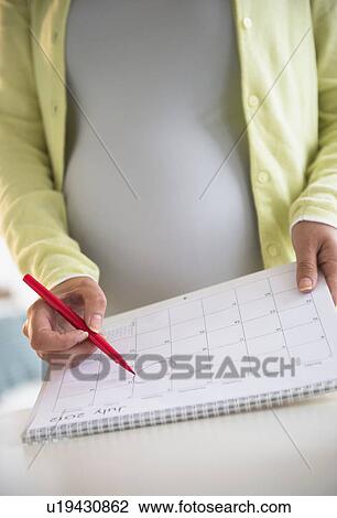 Stock Image - Pregnant woman with calendar. Fotosearch
