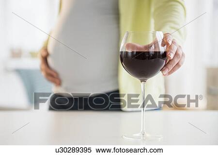 Stock Photography - Pregnant woman with glass of red wine. Fotosearch