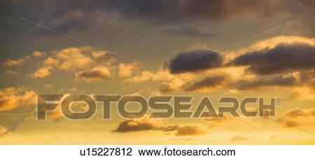 Stock Image - Puffy clouds at sunset. Fotosearch